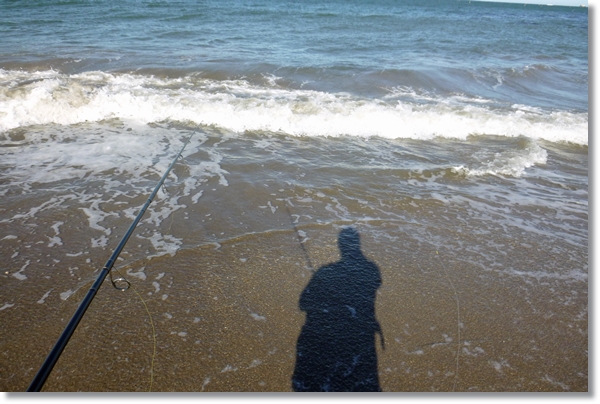 波打ち際に映る釣り人の影
