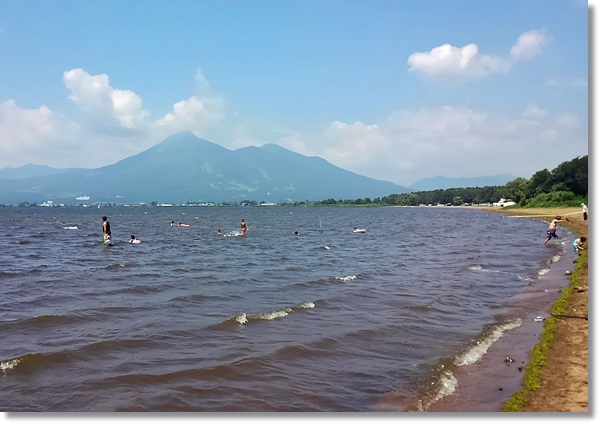 磐梯山がの見える猪苗代湖で水遊びをする人々